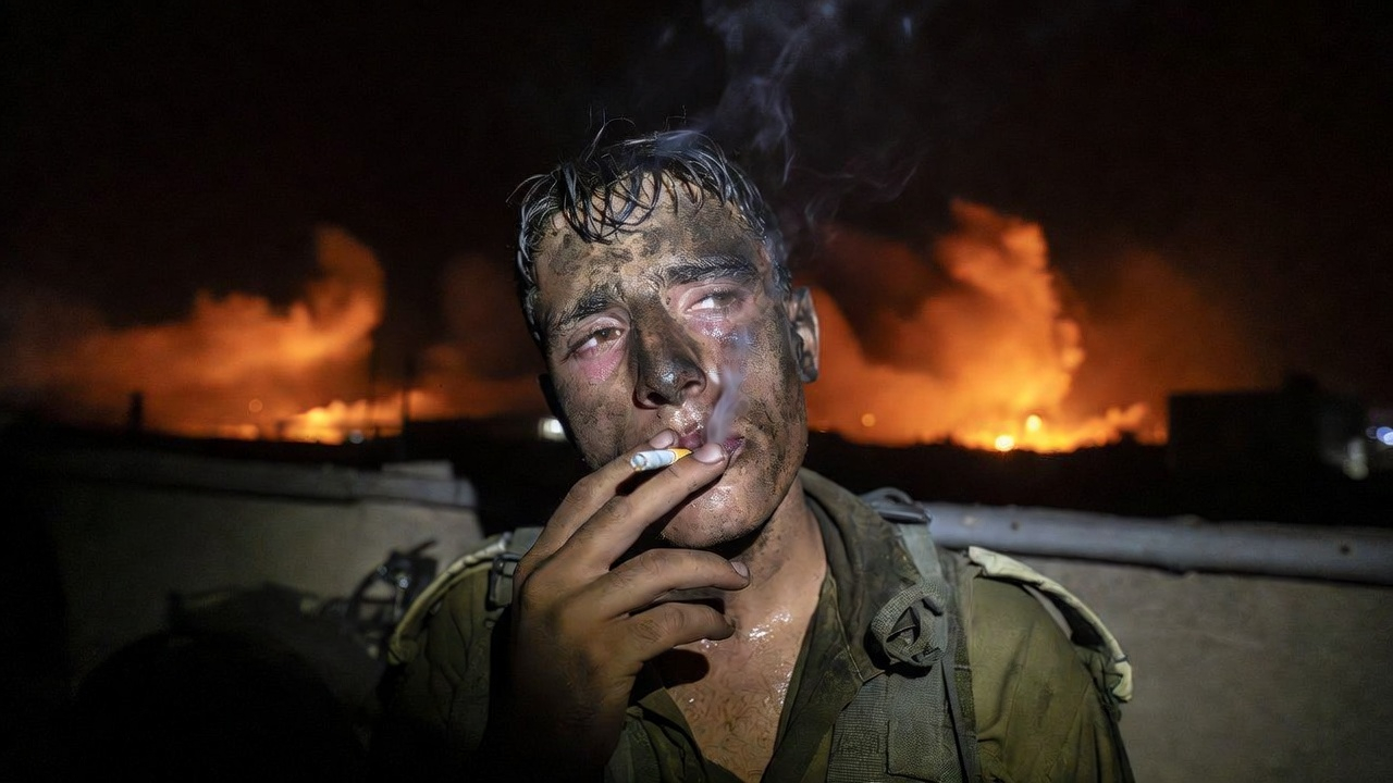 Exhausted IDF soldier smoking in a rooftop bunker lit by explosion flashes